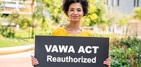 Woman holding sign that reads "VAWA ACT Reauthorized"