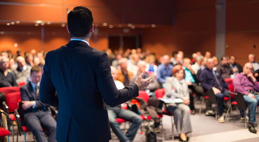 Man standing in front of adult audience lecturing