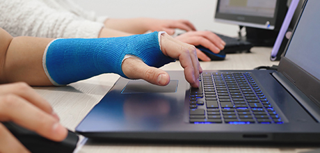 Cast hand typing on laptop