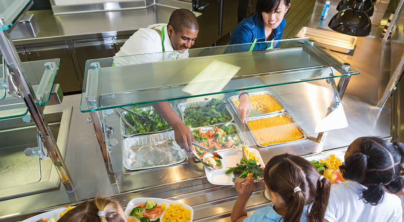 Adults serving lunch to kids in school