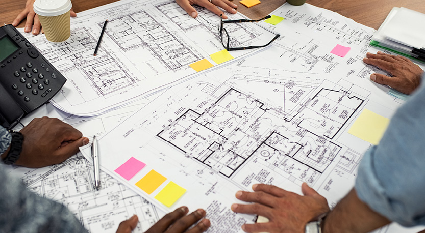 3 people reviewing blueprints on a desk