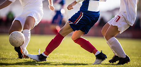 Soccer player running with ball while avoiding her opponent