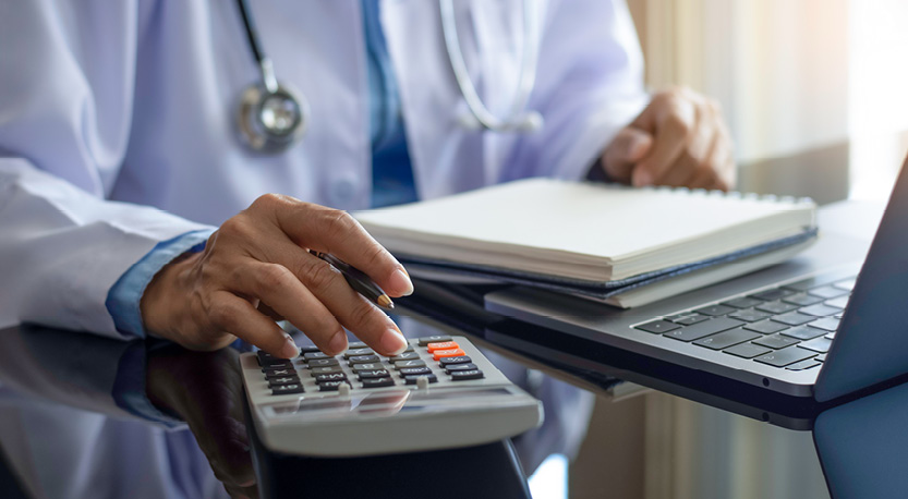 Doctor looking at paperwork and utilizing a calculator