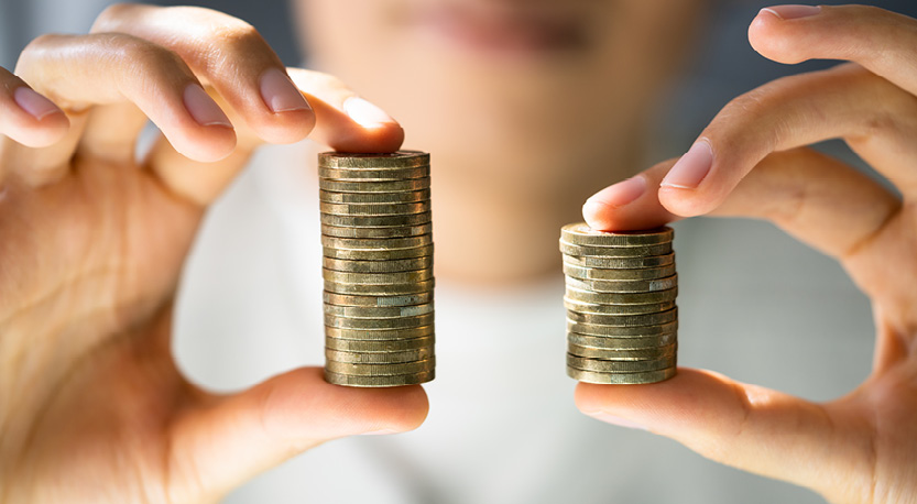 two hands hold up a stack of quarters in between their thumb and forefinger