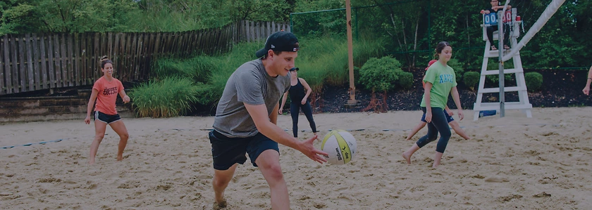 Chris Groeschen serves the ball on a sand volleyball court.